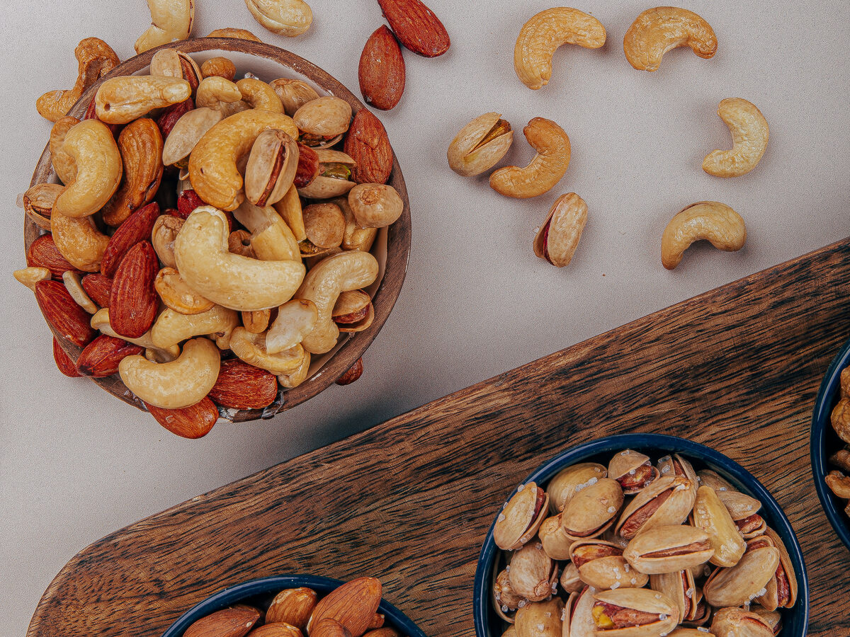 Schalen mit Cashewkernen, Mandeln und Pistazien auf einem Holzbrett